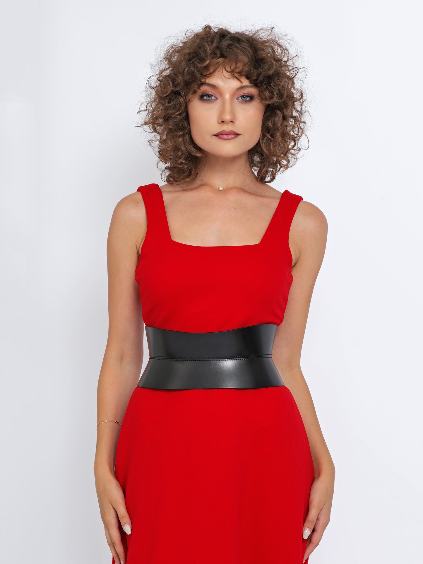 Front view of black leather corset belt being worn over red dress.