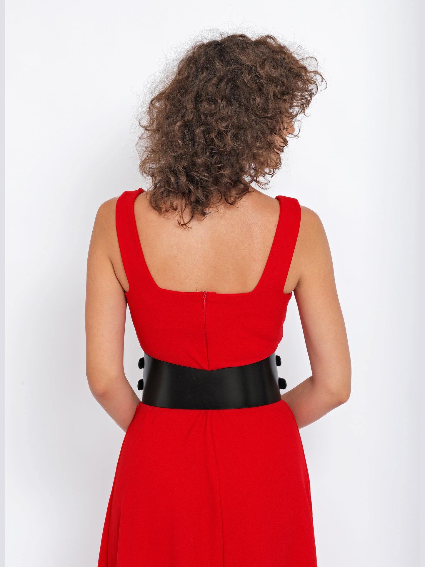 Back view of black leather belt being worn over red dress.