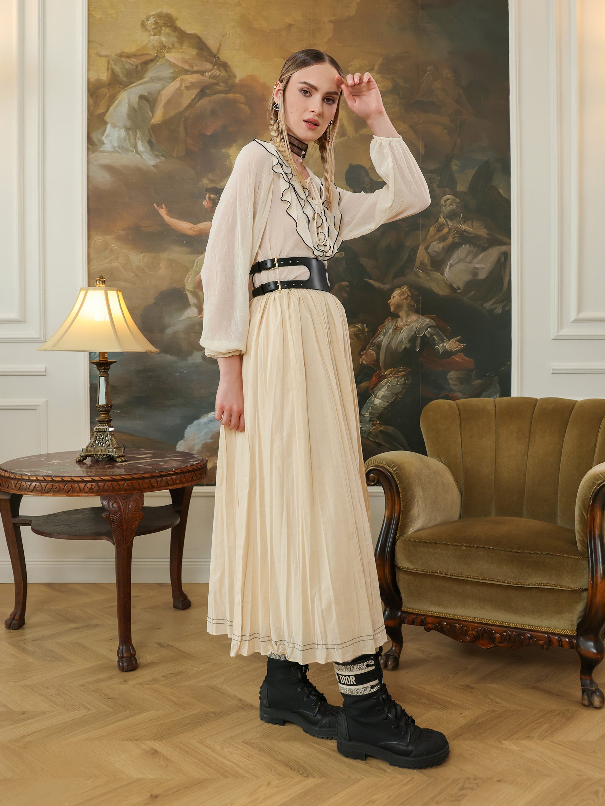 Woman in a white blouse and beige skirt wearing a elegant black leather belt.