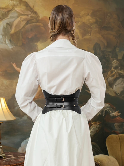 Back view of a woman in a white dress shirt with a black leather hourglass corset belt featuring double buckle straps.