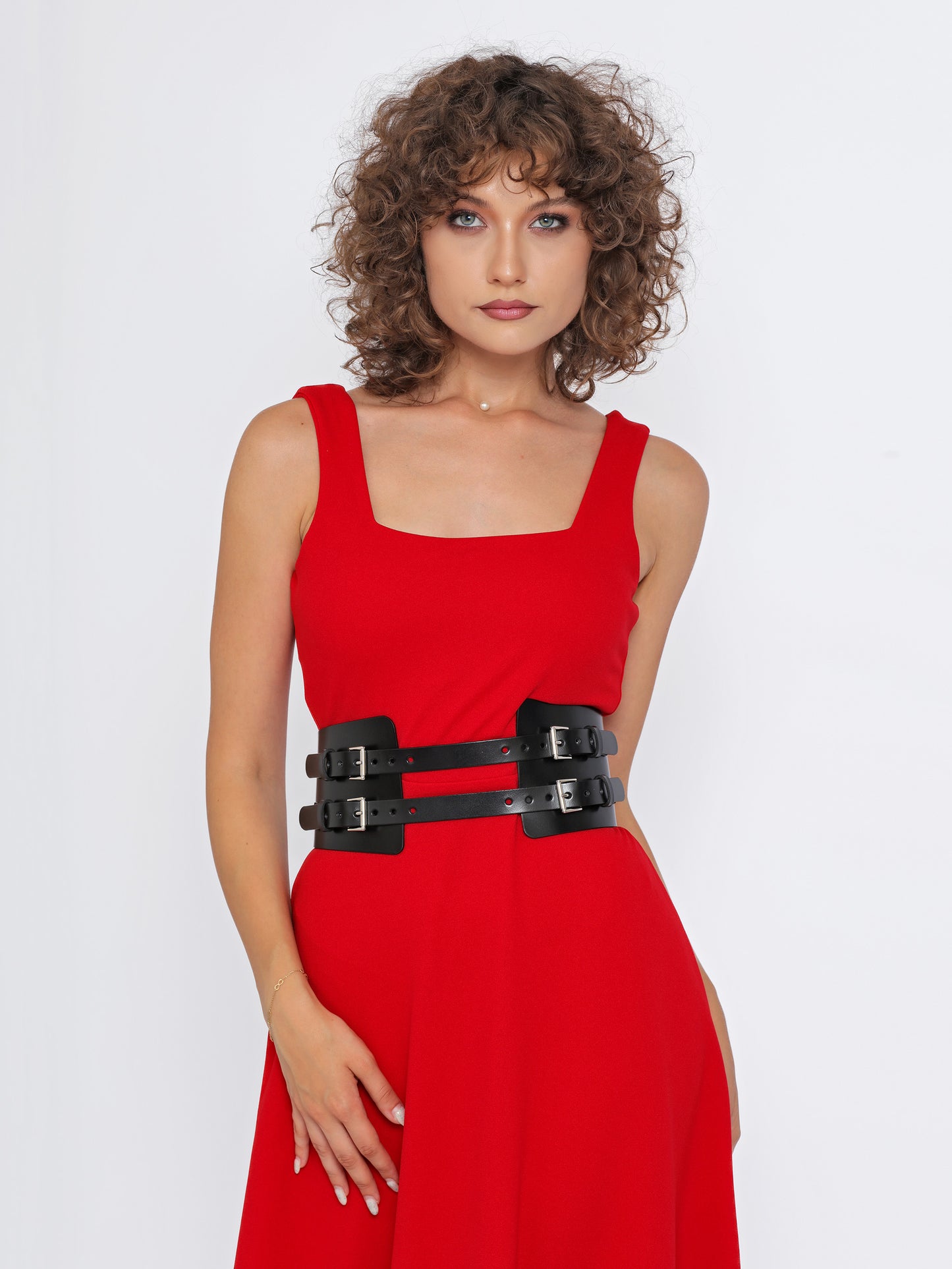 Front view of black leather corset belt being worn over red dress.