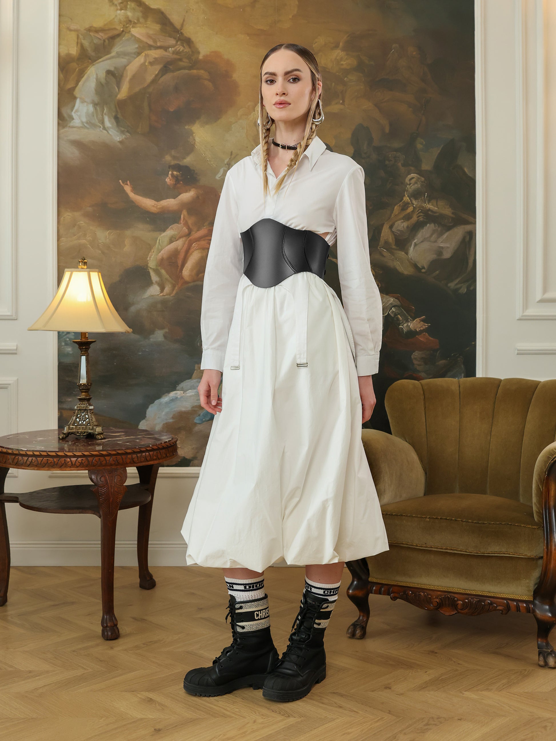 Full outfit featuring a black leather corset belt styled with a white dress, Dior socks, and lace-up combat boots.