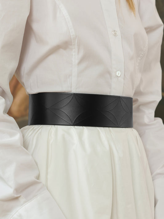 Close-up of a black wide leather belt with subtle embossed pattern at the waist.