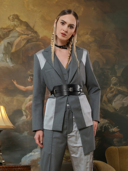 Statement wide leather belt cinching waist of modern grey pantsuit.