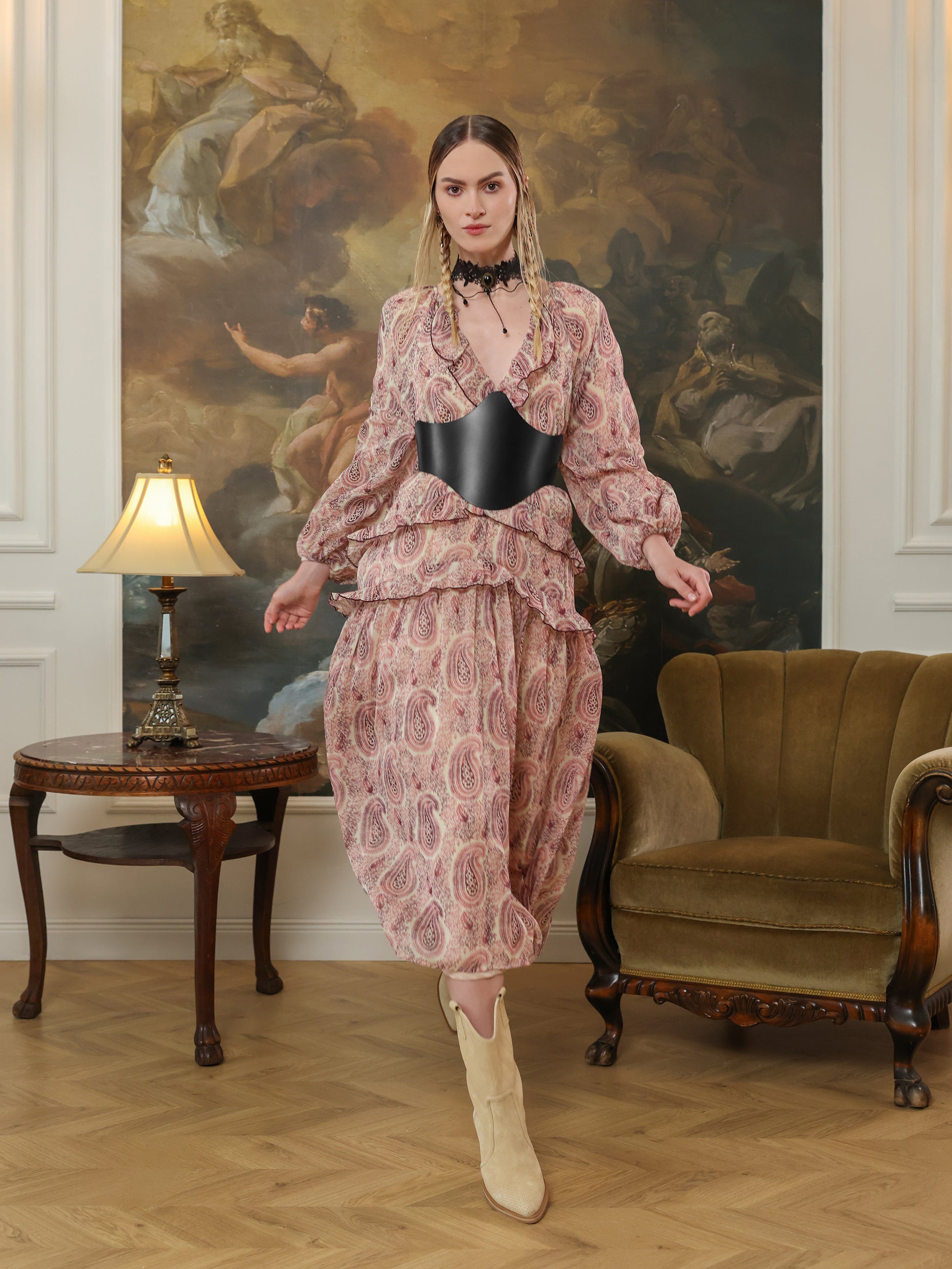 Full outfit shot of a paisley dress styled with a black leather underbust belt and beige boots.