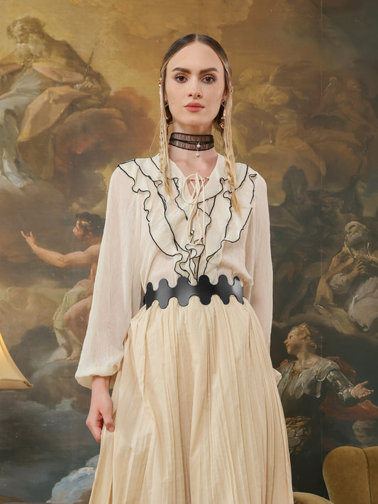 Front view of a black high-waist belt with wave-edge detail paired with a ruffled cream blouse and pleated skirt.