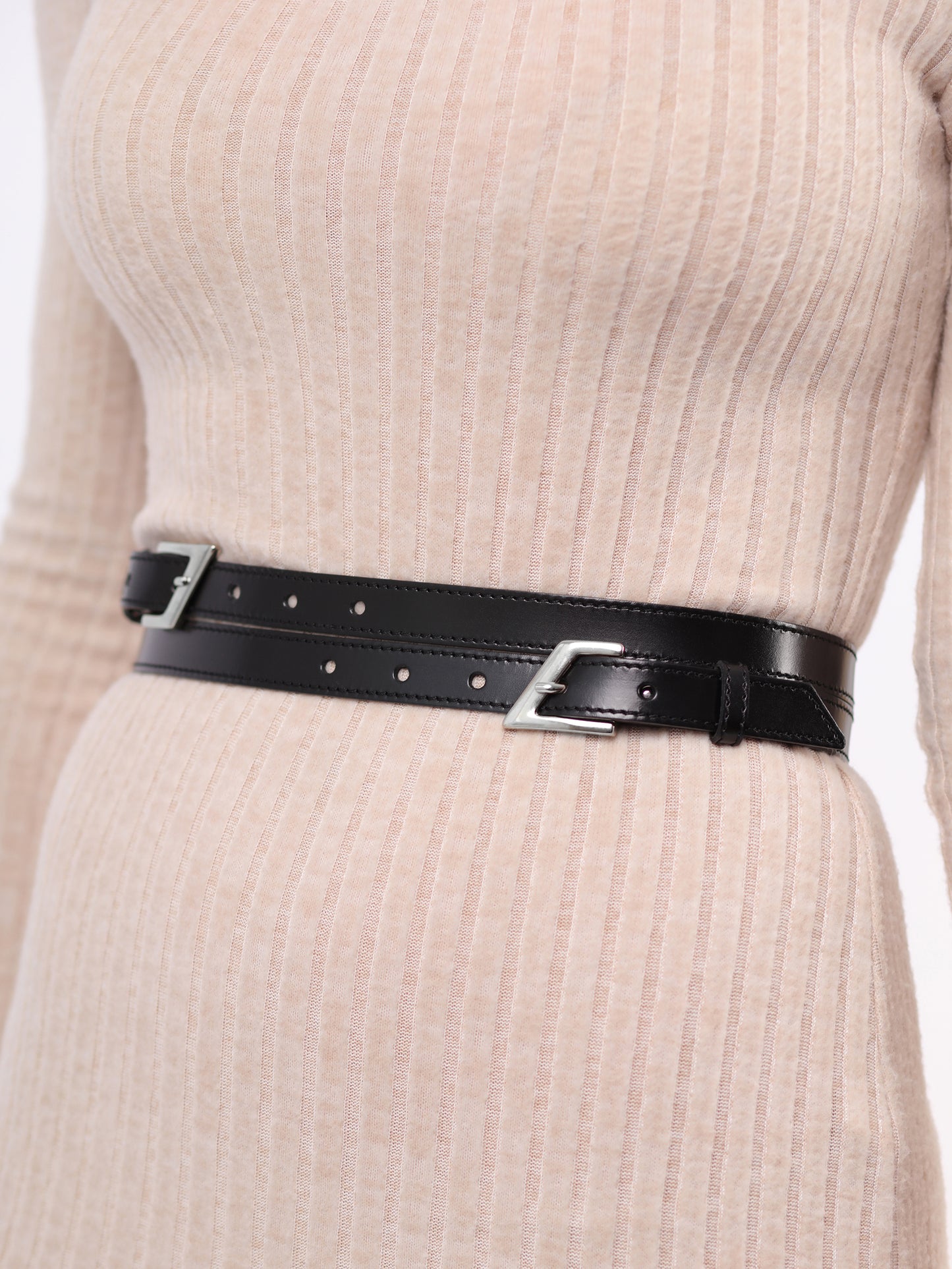 Detailed view of black leather double buckle belt. 