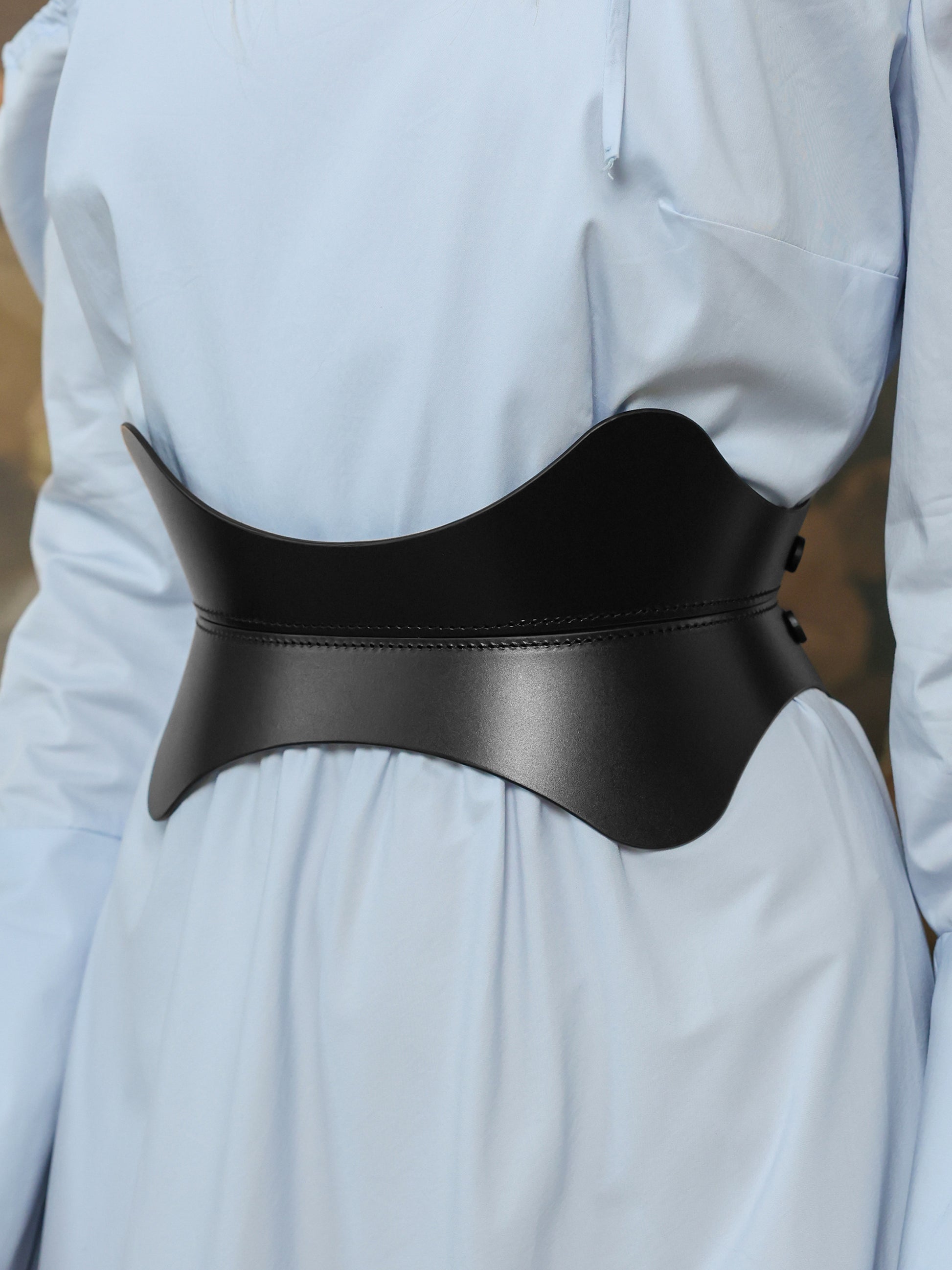 Women’s hourglass waist belt in black leather styled with a flowy pastel blue maxi dress.