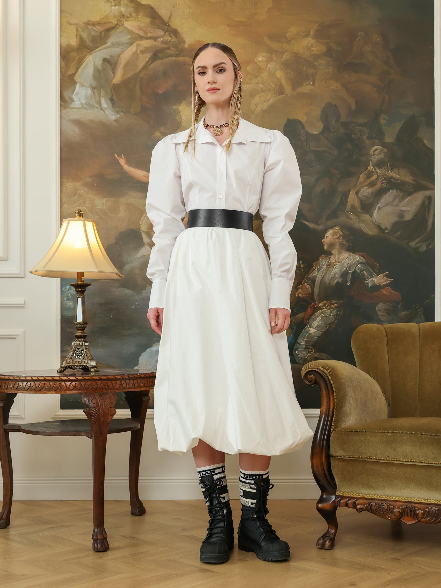 Full outfit view of a wide leather waist belt styled with a white dress and black combat boots.
