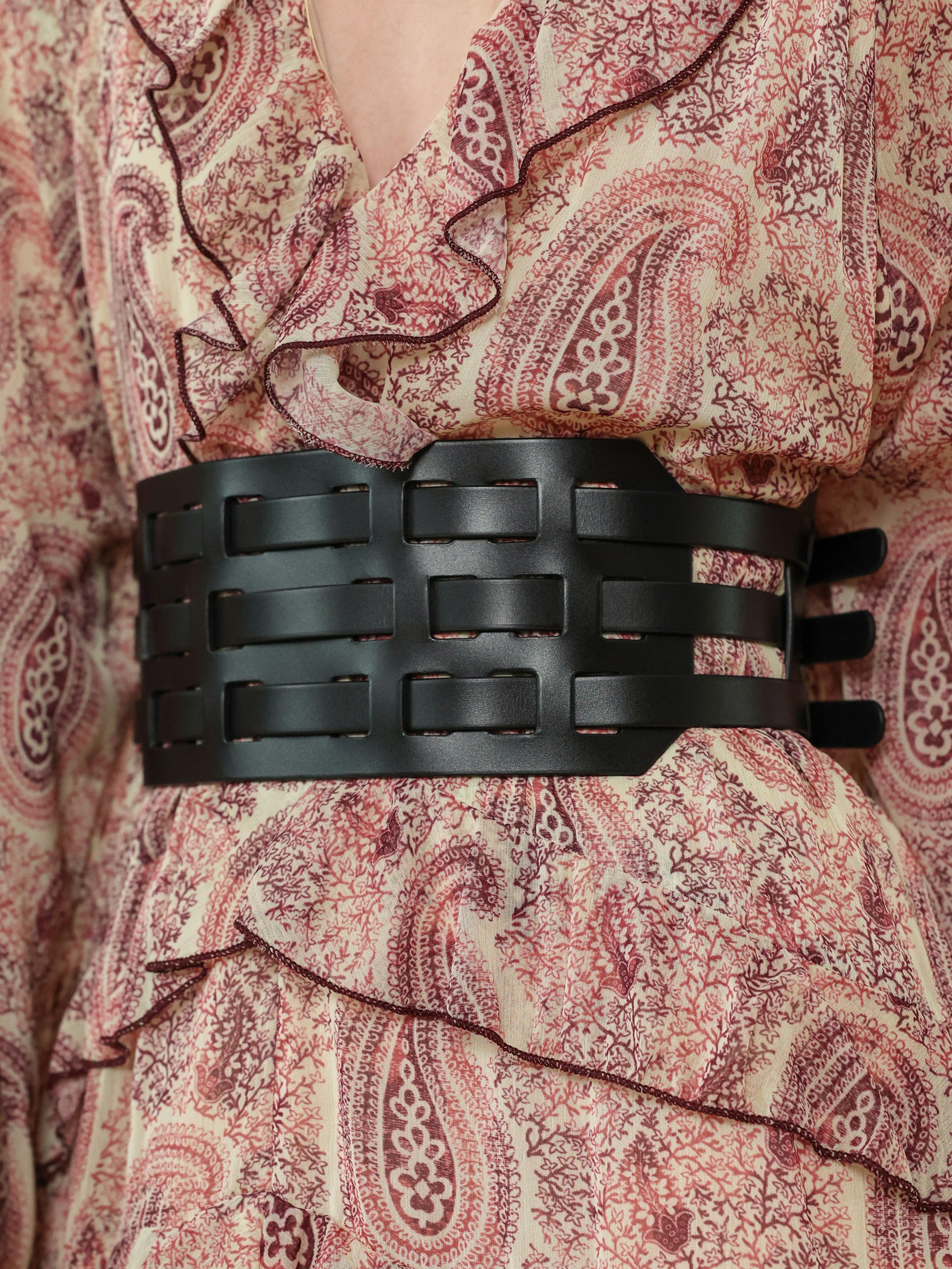 Women's wide fashion belt in black leather, adding structure to a printed dress outfit.