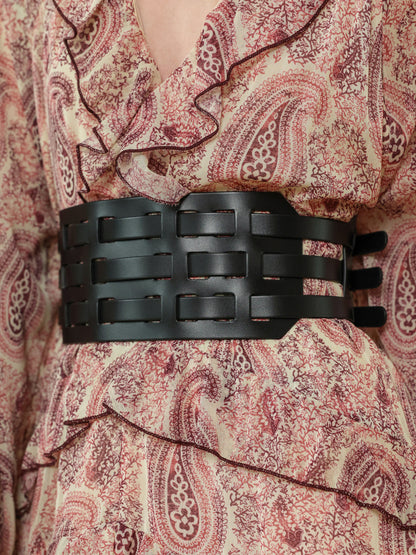 Women's wide fashion belt in black leather, adding structure to a printed dress outfit.