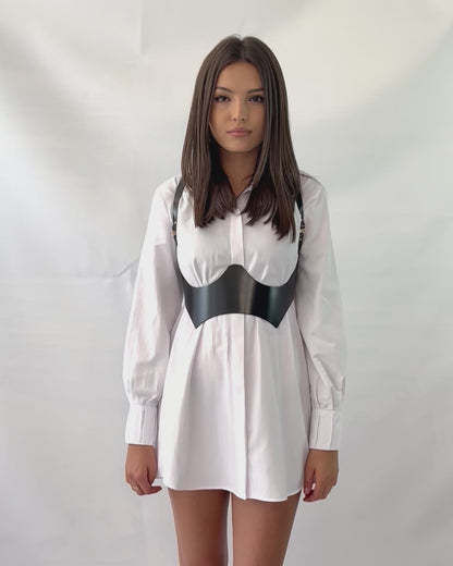 Video presenting underbust leather harness worn over shirt dress.