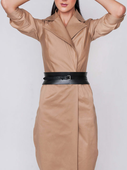 Front view of black leather corset belt worn by woman over beige coat.