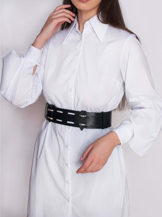 Front view of black leather waist cincher belt worn by woman over a white shirt.
