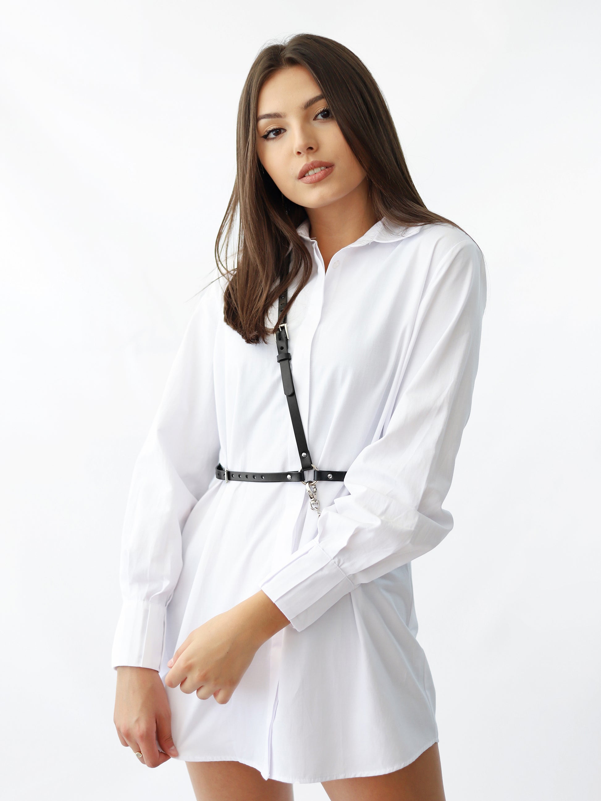 Slim leather chain harness worn over white shirt dress.