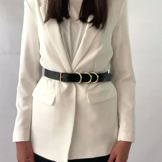 Gold hardware leather belt fitted on white blazer.