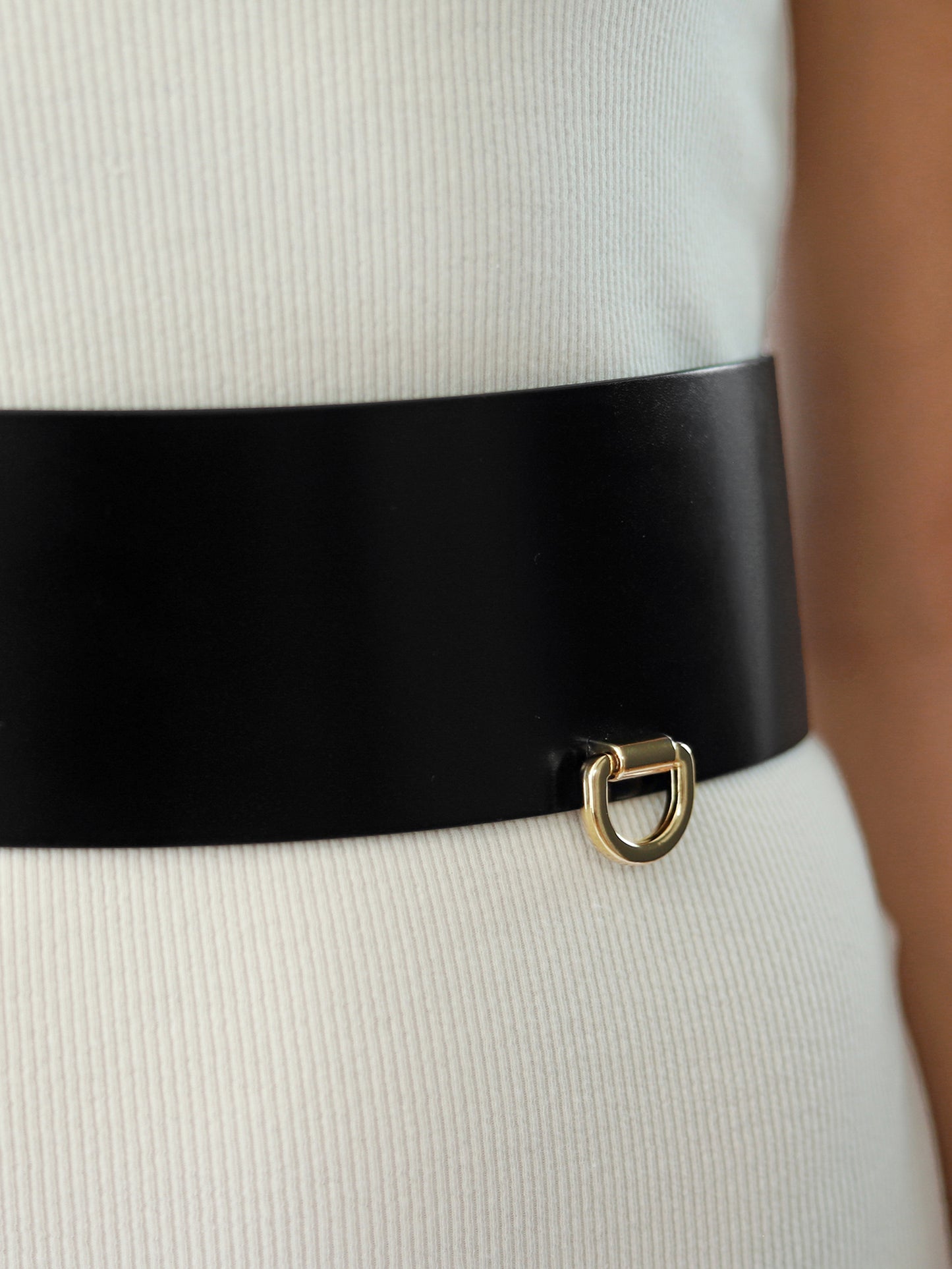 Detailed view of black leather wide belt.