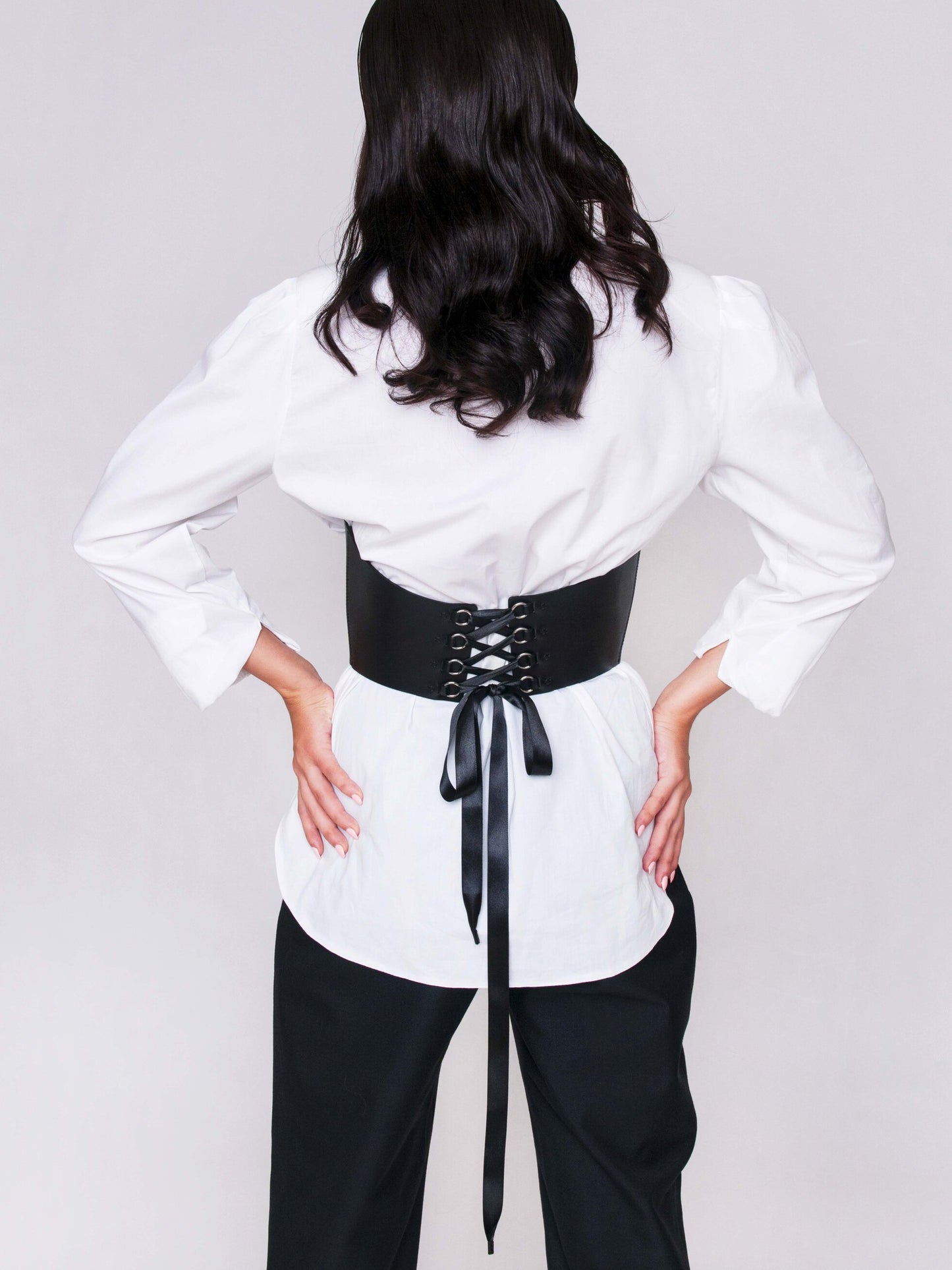 Back view of underbust corset lacing worn by woman.