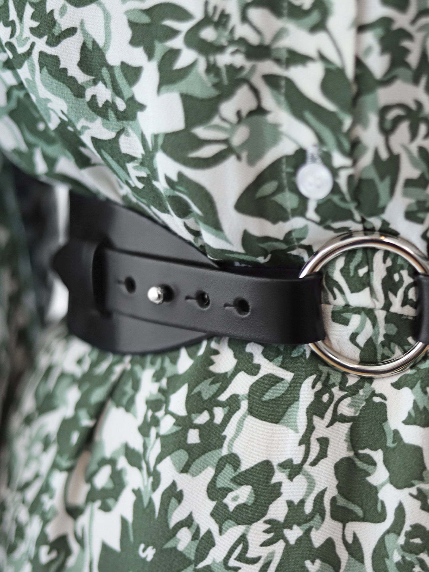 Detailed view of black leather harness belt.