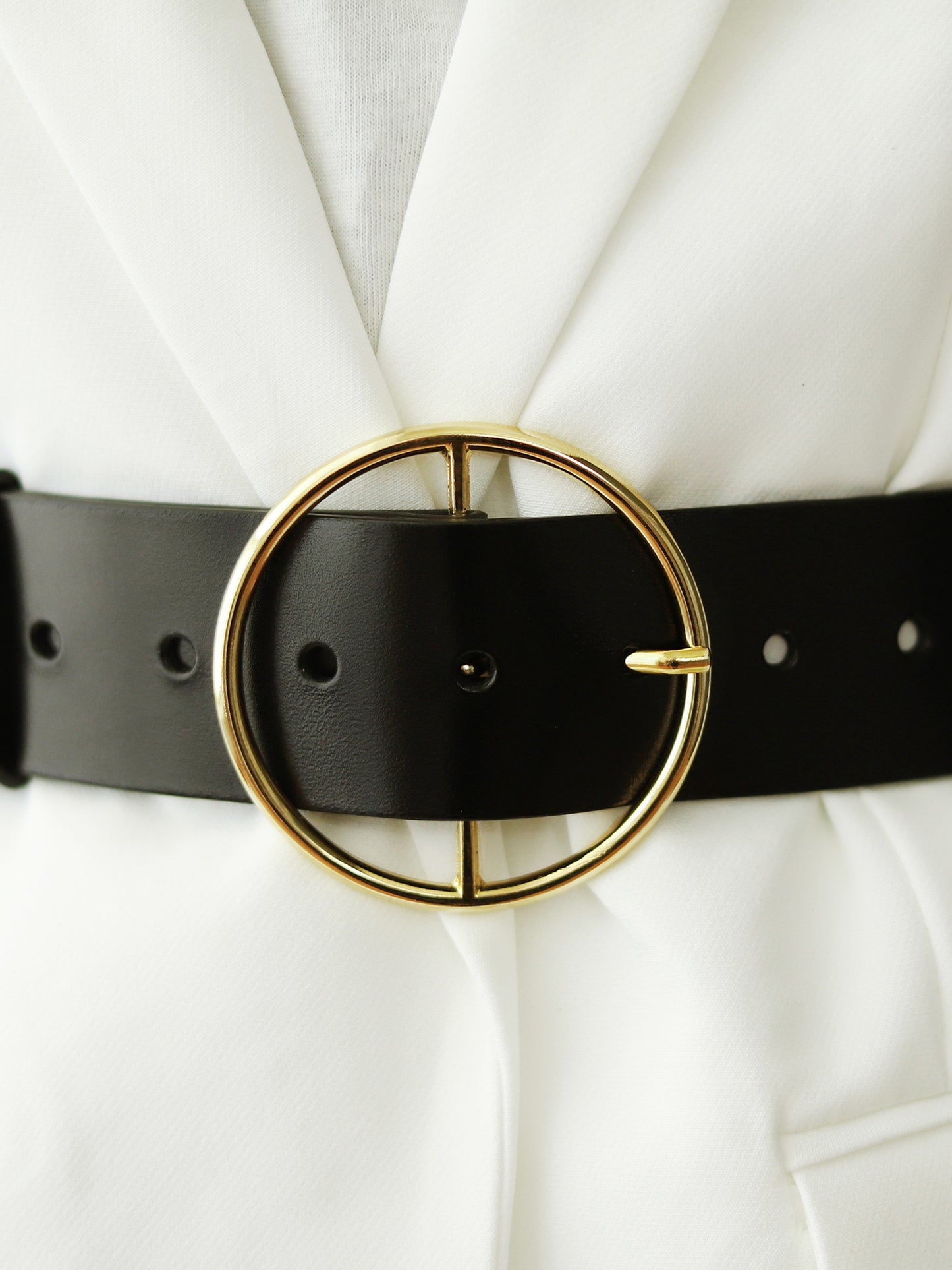 Detailed view of round buckle leather belt.