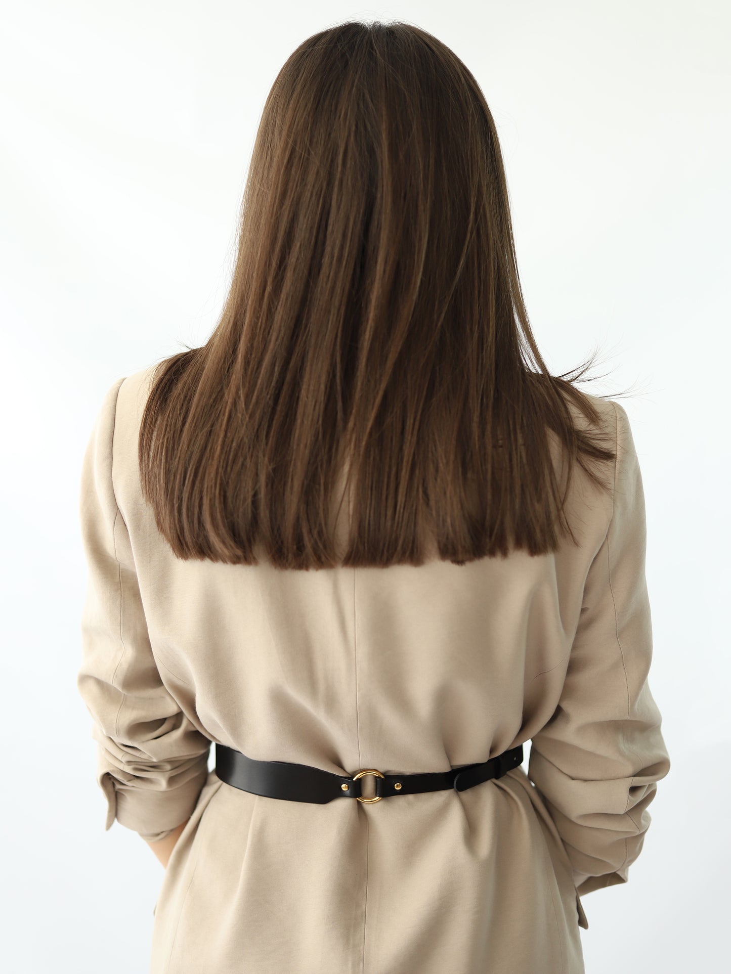 Back view of skinny leather belt worn over beige blazer.