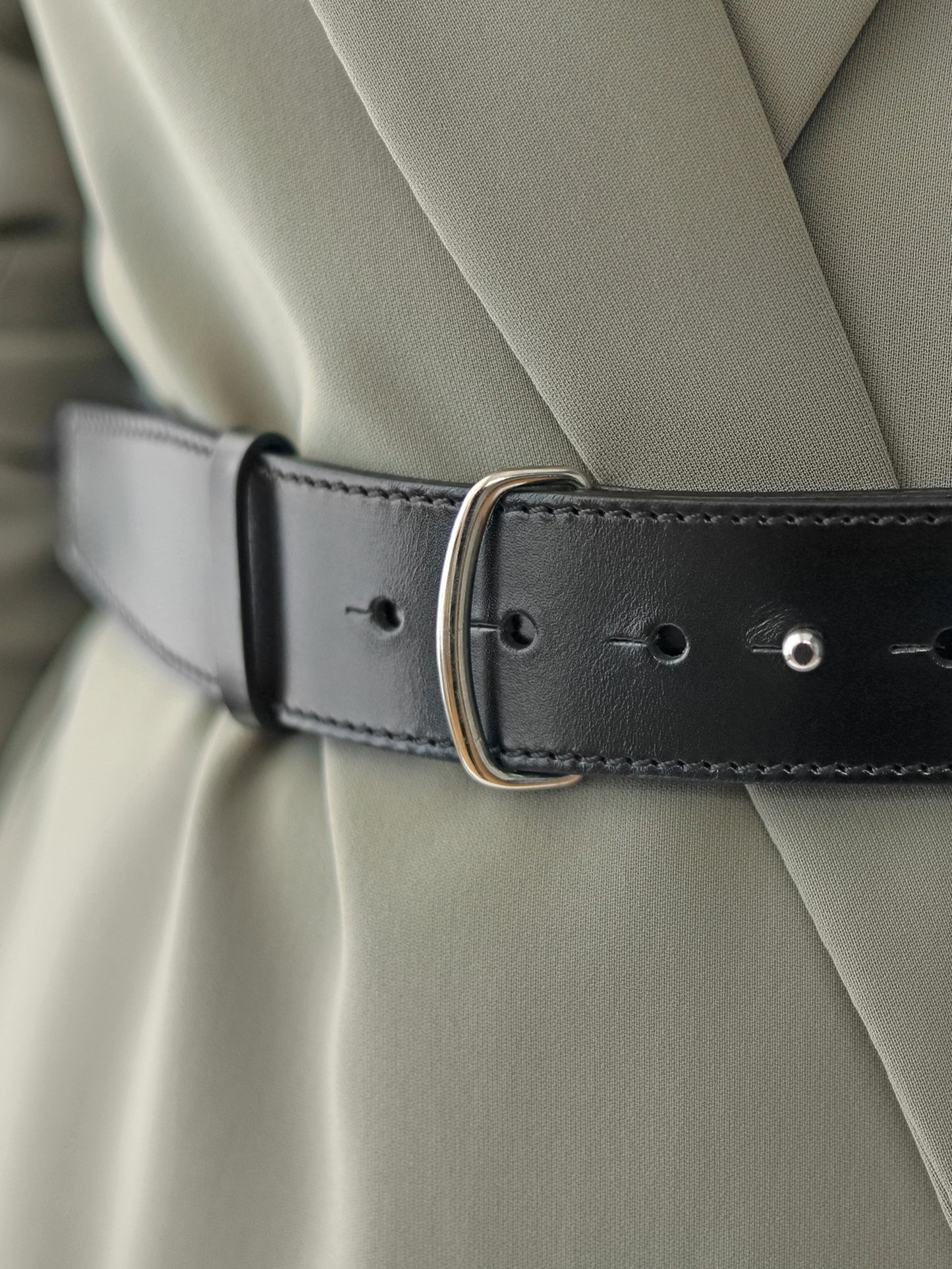Detailed view of women black leather belt.