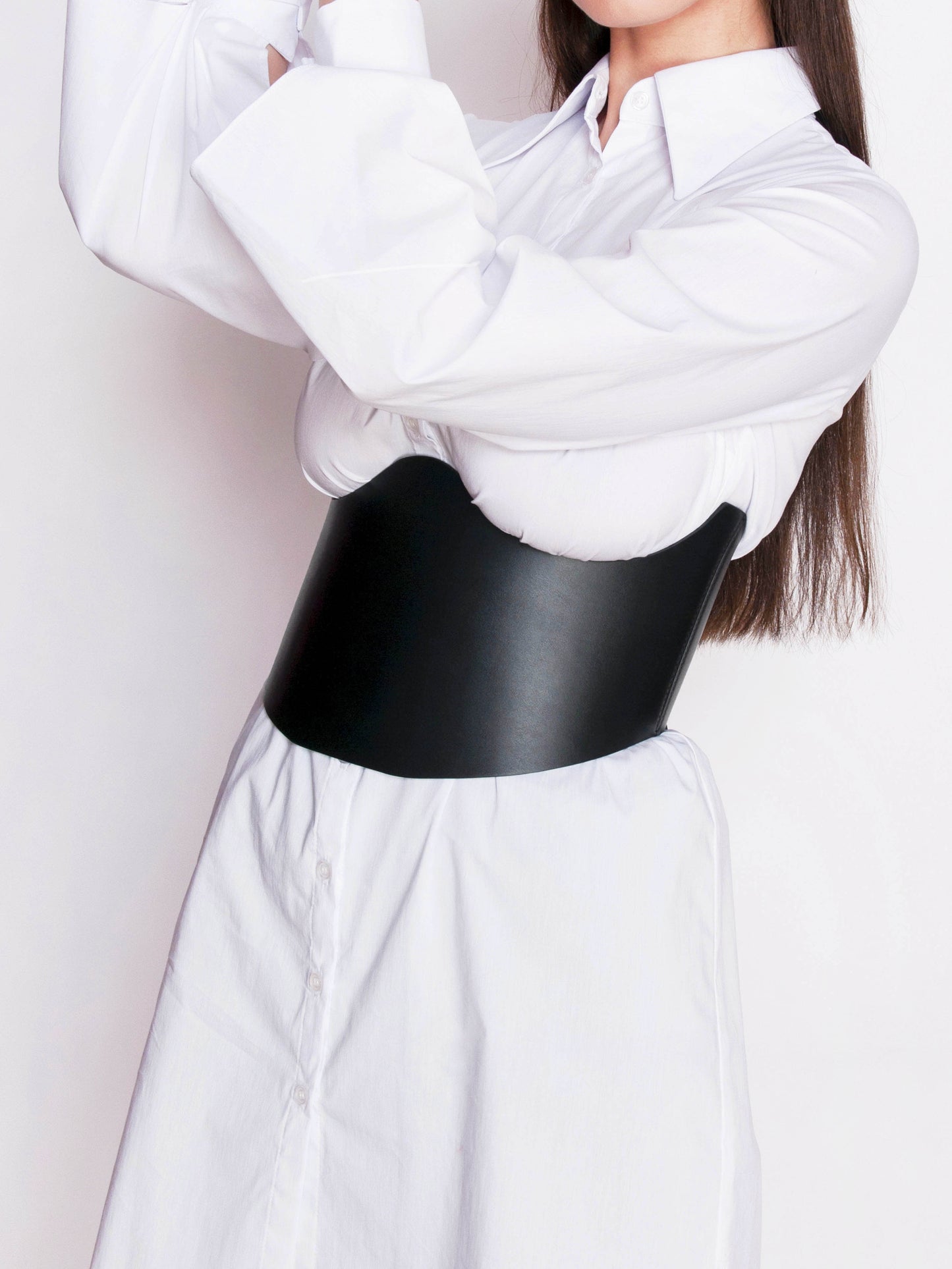 Side view of black underbust corset worn by woman over white shirt.