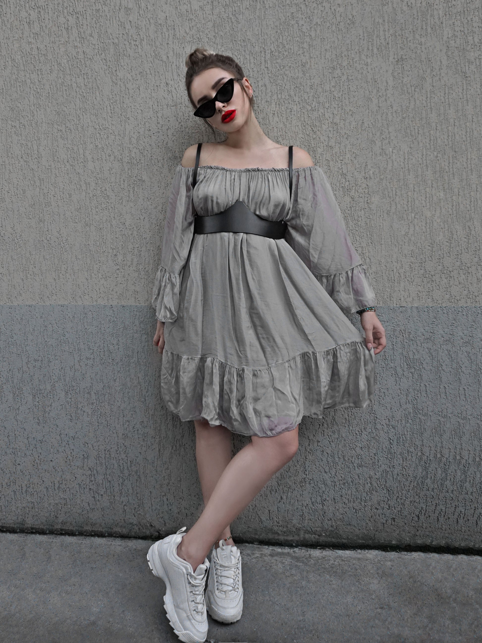 Black leather underbust harness worn with gray dress and white sneakers. 