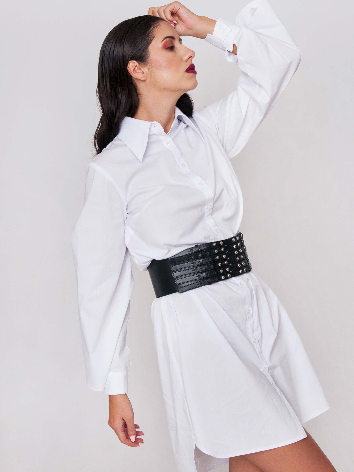 Side view of waist cincher belt worn by a woman over white dress shirt.