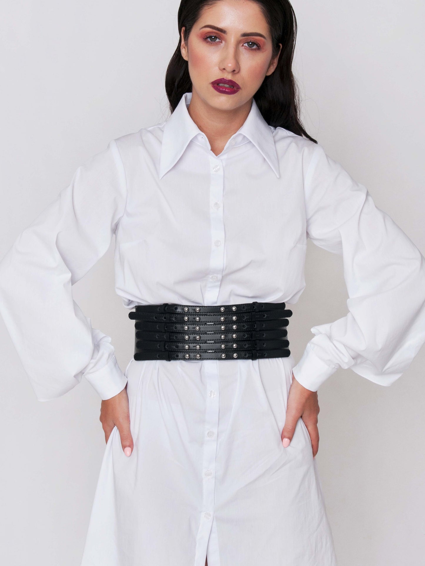 Front view of black wide belt worn by a woman over a white dress shirt.