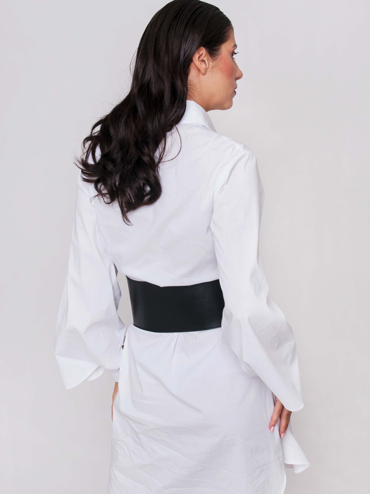Back view of wide waist belt worn by woman over a white shirt dress.
