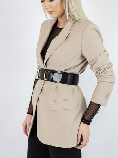 Black leather wide belt worn over beige blazer.